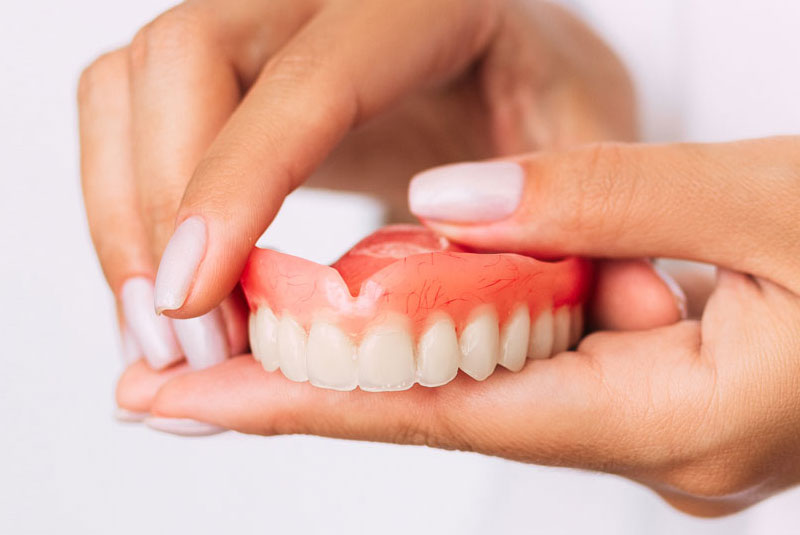 women holding traditional denture model